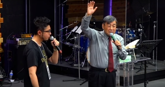 Pastor Hiraoka Shuuji (direta) alerta para a urgência de um movimento missionário no Japão. (Foto: YouTube/Reprodução)