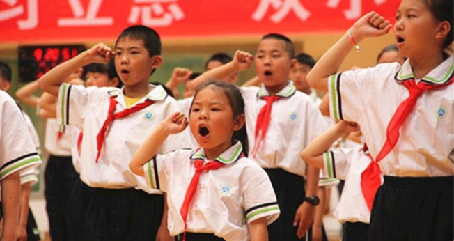 'Jovens Pioneiros' em uma escola primária na região autônoma de Ningxia Hui fazem um juramento durante uma atividade do evento "O Lenço Vermelho Segue a Festa" no Dia das Crianças. (Foto: Bitter Winter)
