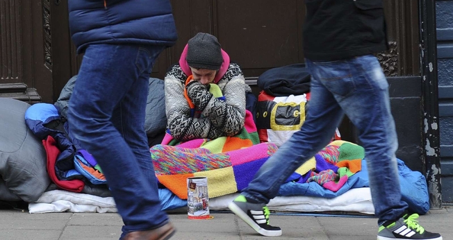 Pedestres passam por um morador de rua no Reino Unido. (Foto: Daniel Sorabji/AFP)