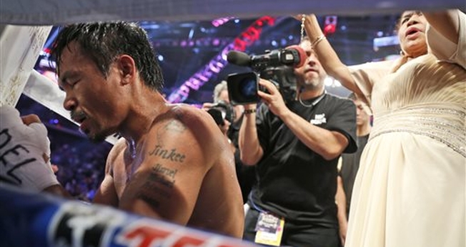 Manny Pacquiao em oração após disputa pelo título dos meio-médios em Macau, na China, em 2014. (Foto: AP)