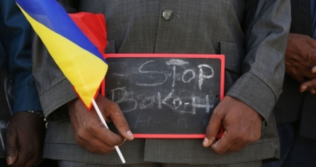 Homem segura uma pequena placa que diz "Pare, Boko Haram", em um evento para apoiar as tropas militares de Chade