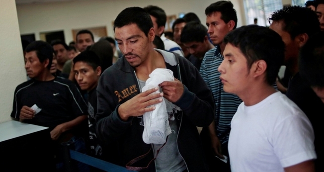 Imigrantes ilegais aguardam enquanto recebem seus pertences e processam sua volta ao aeroporte de La Aurora (Guatemala), de onde saíram.