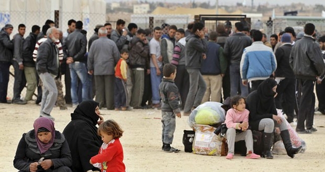 Refugiados aguardam do lado de fora de um campo, na Jordânia. Imagem do final de 2013. (Foto: Muhammad Hamed/Reuters)