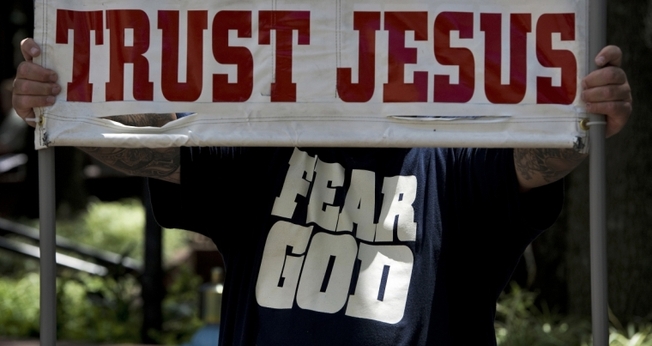 "Confie em Jesus", afirma cartaz, em inglês, durante ação de evangelismo. (Foto: Reuters)