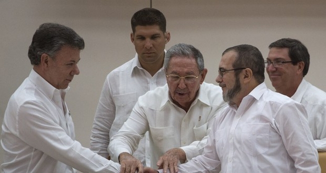 Presidente da Colômbia Juan Manuel Santos e o líder das FARC Timoleón Jiménez cumprem ato simbólico para acordo de paz, na frente do presidente cubano Raúl Castro (Foto: AP Photo / Desmond Boylan)