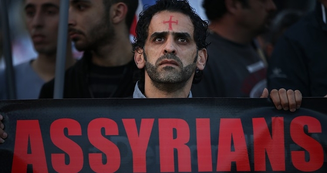 Um homem assírio caminha durante um protesto unido a centenas de pessoas. (Foto: Reprodução/The Wall Street Journal)