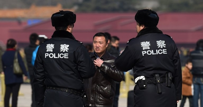 Policiais interrogam um homem na Praça Tiananmen, em Pequim. (Foto: Greg Baker/Agence France-Presse — Getty Images)