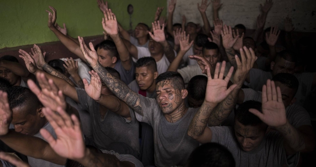 Antigos membros de gangues, presos na cadeia de Gotera, levantam as mãos durante o culto. (Foto: Victor Peña/El Faro)
