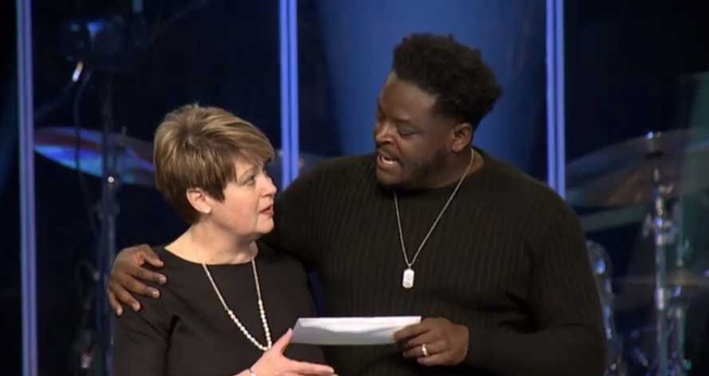 O pastor Derwin Gray entrega doação para Julie Walters, do Centro de Enriquecimento das Mulheres. (Foto: Reprodução/Facebook)