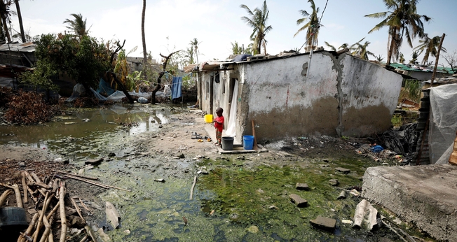 Criança ao lado de poças de água parada em Beira, Moçambique, nesta quarta-feira (27) (Foto: Mike Hutchings/Reuters)