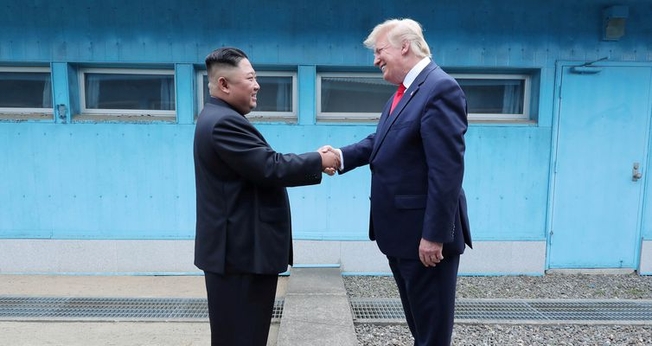 Trump em aperto de mãos com Kim na linha de demarcação que divide as duas Coreias. (Foto: KCNA via Reuters)