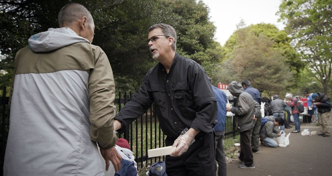 Mark Bennett acolhe um morador de rua na capela da calçada no Parque Yoyogi, em Tóquio. (Foto: Reprodução/IMB)