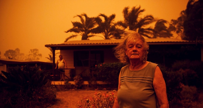Casal do lado de fora enquanto forte vento empurra a fumaça do incêndio em direção a Nova Gales do Sul, na Austrália. (Foto: Tracey Nearmy/Reuters)