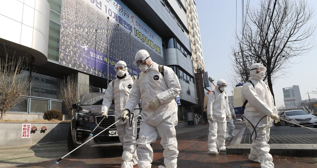 Trabalhadores com equipamento protetor usam desinfetante em spray contra o novo coronavírus em frente à igreja em Daegu, na Coreia do Sul, nesta quinta-feira (20). (Foto: Kim Jun-beom/Yonhap via AP)