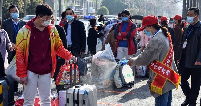 Voluntária aplica desinfetante sobre a bagagem de um aluno em Bozhou, na província de Anhui, no leste da China. (Foto: AFP)
