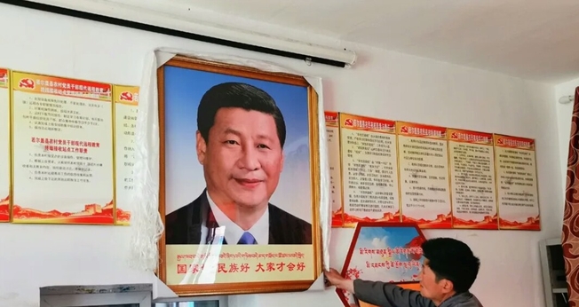 Homem pendura um retrato do presidente chinês Xi Jinping, no condado de Dzoge, no leste do Tibete. (Foto: Free Tibet)