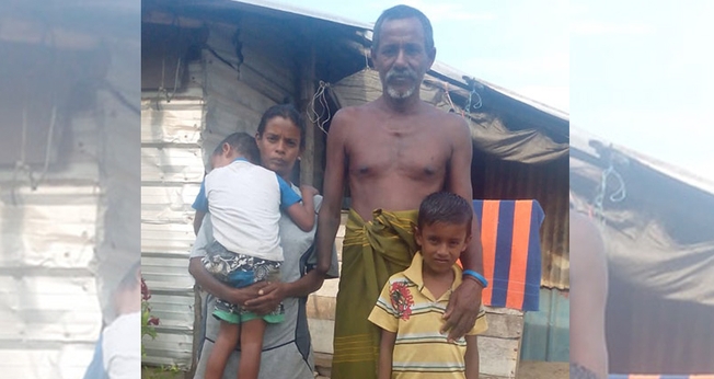 Khanjana ao lado da esposa e dois filhos, em frente à cabana da família. (Foto: Gospel For Asia)