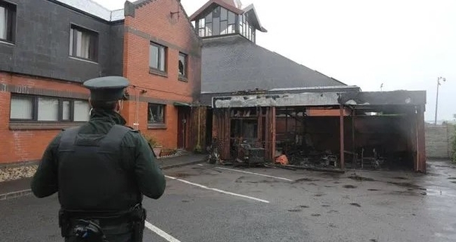 Policial observa igreja incendiada na Irlanda do Norte. (Foto: Reprodução / Bíblia Todo)