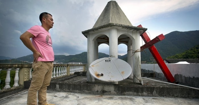 Líder de igreja permanece em pé no teto do templo, após o local ter sua cruz removida, na província de Zhejiang. (Foto:  Mark Schiefelbein/AP)
