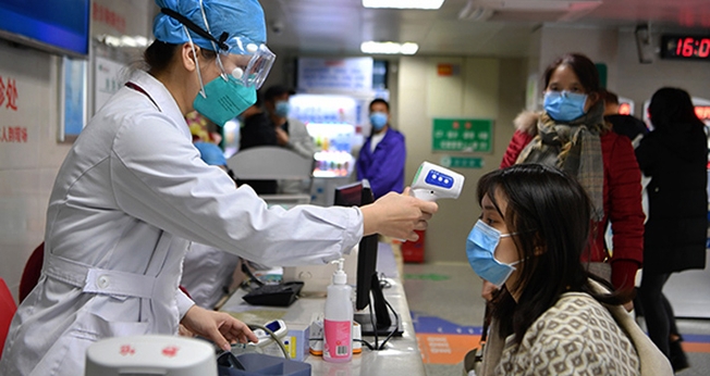 Profissional de saúde checa temperatura de mulher em um hospital de Fuzhou, na China. (Foto: Xinhua)