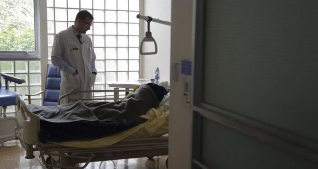 O Dr. Stephane Mercier visita um paciente na unidade de cuidados paliativos do hospital AP-HP Paul-Brousse em Villejuif, perto de Paris. (Foto: Reuters)