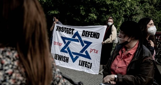 Participantes de uma vigília contra o antissemitismo se reúnem em frente à sinagoga em Kreuzberg, Berlim, no domingo. (Foto: Filip Singer / EPA)