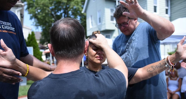 Pastor Steve Hannett ora por mulher durante batismo. (Foto: Abundant Grace Christian Church)