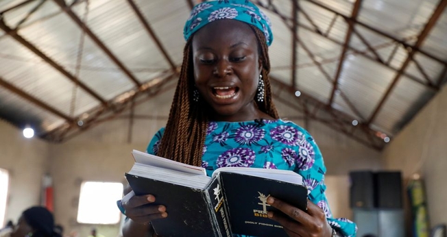 Mulher e a Bíblia Pidgin durante culto na Igreja do Cidadão Celestial em Lagos, Nigéria. (Foto: Reuters / Temilade Adelaja)