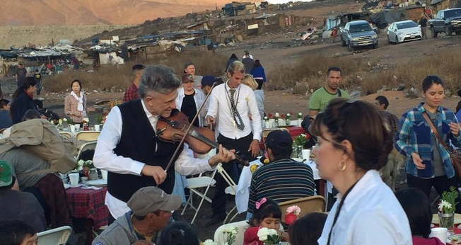 O evangelista Georgian toca violino durante ação social em comunidade pobre. (Foto: Reprodução/Facebook).
