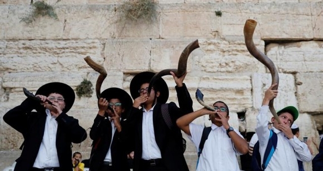 Judeus ultraortodoxos tocam o shofar enquanto os fiéis oram no Muro das Lamentações. (Foto: Reprodução / El País)