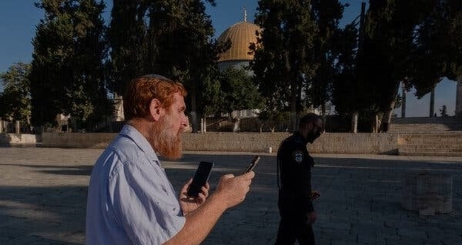 O rabino Yehudah Glick orando no Monte do Templo, em agosto de 2021, enquanto um policial patrulhava nas proximidades. (Foto: Amit Elkayam/The New York Times).