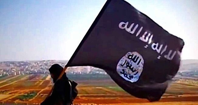 Terrorista com a bandeira do Estado Islâmico na cidade de Dabiq, na Síria, em 2013. (Foto: Wikimedia Commons)