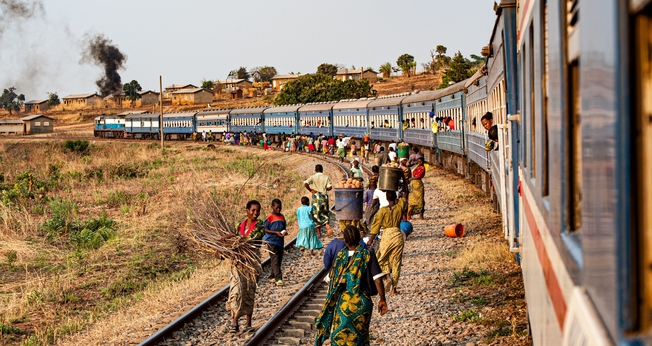 Multidões caminham ao lado de um trem estacionado na Zâmbia. (Foto: Katsuma Tanaka/Unsplash)