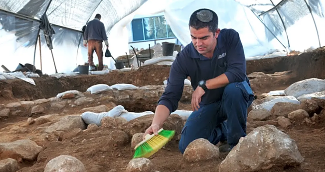 Kfir Arbiv, diretor de escavação da Autoridade de Antiguidades de Israel, limpa uma pedra balista no Complexo Russo. (Foto: Yoli Schwartz/Israel Antiquities Authority)