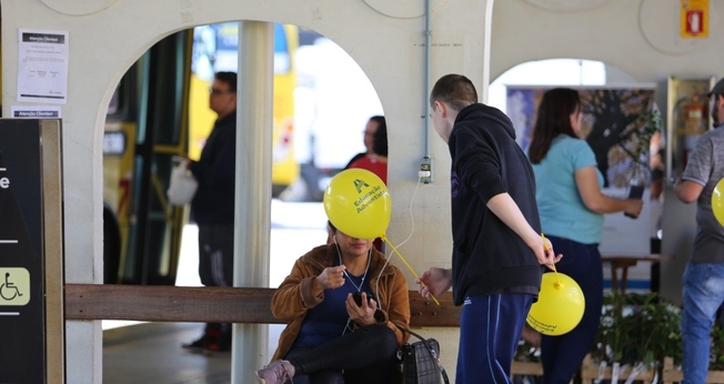 Estudante entrega balão e conversa com passageira no terminal de ônibus. Alunas posam para foto durante mobilização em semáforos. (Foto: Paulo Ribeiro)