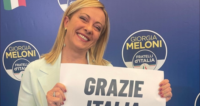 Giorgia Meloni durante discurso à imprensa, segurando placa ‘Obrigada Itália’. (Foto: Reprodução/Facebook/ Giorgia Meloni)