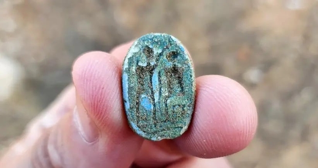 O escaravelho, mostrando uma figura sentada à direita e uma figura em pé com o braço erguido à esquerda. (Foto: Gilad Stern/Israel Antiquities Authority)