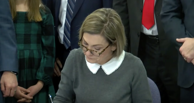 A governadora de Iowa, Kim Reynolds, enquanto assina nova legislação. (Captura de tela/ YouTube/We Are Iowa Local 5 News)