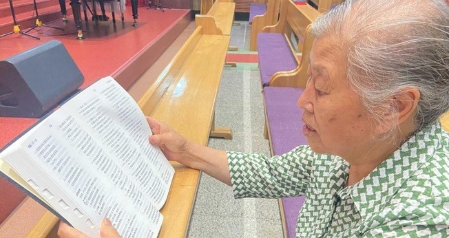 Zheng Yuzhen lendo sua Bíblia nova. (Foto: Reprodução/Bible Society/UBS-CP)