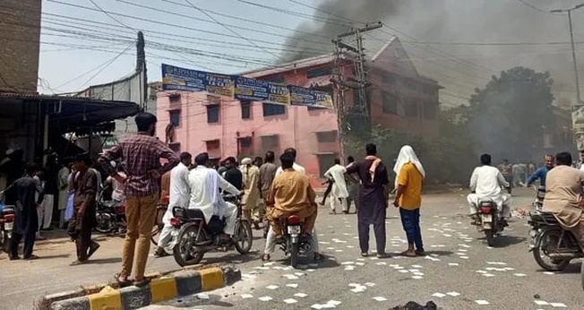 Uma multidão observa a fumaça subir de uma igreja incendiada em Jaranwala, Paquistão, em 16 de agosto de 2023. (Foto: Daud Irshad)