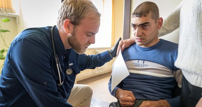 O médico Austin Calhoun ora com um paciente com paralisia cerebral. (Foto: IMB).