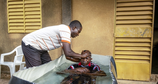 Pastor batiza caminhoneiro convertido por ministério da IMB na África Ocidental. (Foto: IMB)