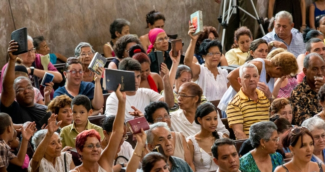 Evangélicos de uma igreja cubana erguem suas Bíblias durante o culto. (Foto: IMB)
