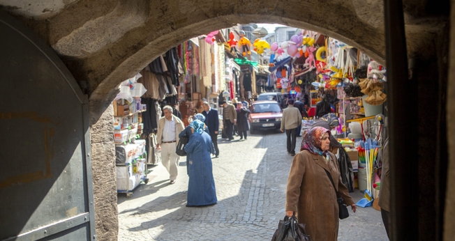 Homens e mulheres caminham por um mercado que vende roupas, alimentos e artigos para o lar em um bairro de Istambul, Turquia. (Foto: IMB)