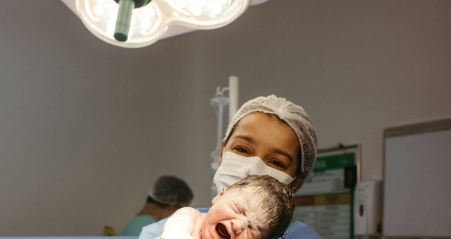 Profissional de saúde segura recém-nascido instantes após o parto. (Foto: Jonathan Borba/Unsplash)