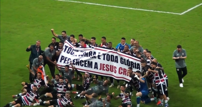 Os jogadores exibiram uma grande faixa exaltando a Jesus. (Foto: Reprodução/YouTube/Roberto Nascimento Conta Aí).