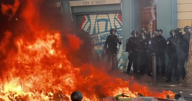 Incêndio durante protestos violentos na França, diante de policiais mobilizados para conter os distúrbios. (Captura de tela/CBS Pittsburgh)