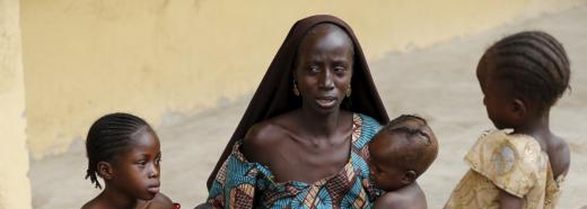Mulher resgatada dos domínios do Boko Haram pelo exército nigeriano alimenta seus filhos em acampamento para refugiados