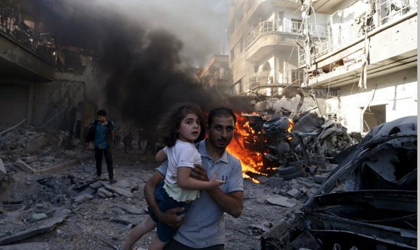 Homem leva uma garota nos braços, enquanto foge de um local atingido por ativistas, no bairro de Douma de Damasco (Síria), em agosto de 2015. (Foto: REUTERS/BASSAM KHABIEH)