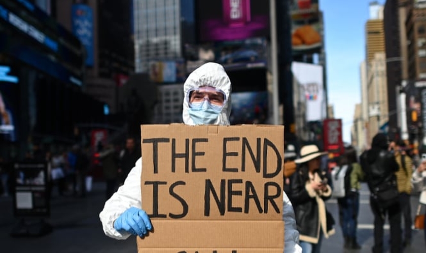 "O fim está próximo", diz manifestante em cartaz sobre coronavírus na Times Square, em Nova York. (Foto: Johannes Eisele/AFP)